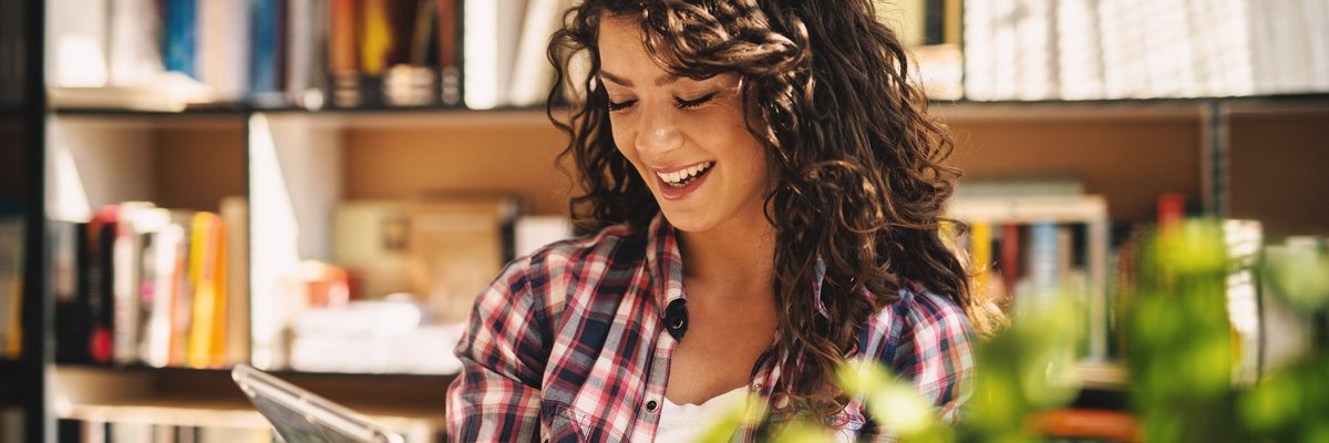 Smiling Young Woman Using Tablet In Library