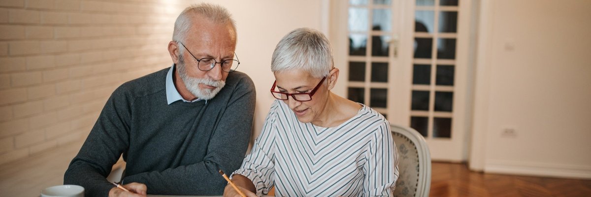 Senior couple analyzing expenses using a notebook and calculator.