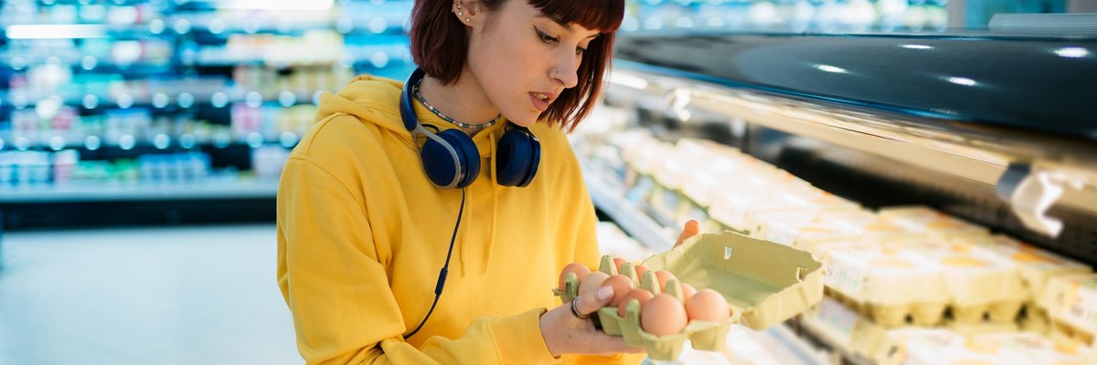 Shopper inspecting a carton of eggs in the grocery store.