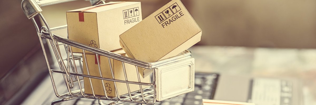 Small shopping cart with boxes on top of a laptop keyboard
