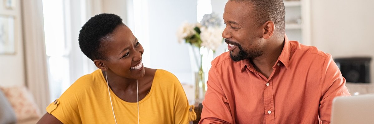 A smiling couple looking at paperwork at a table.