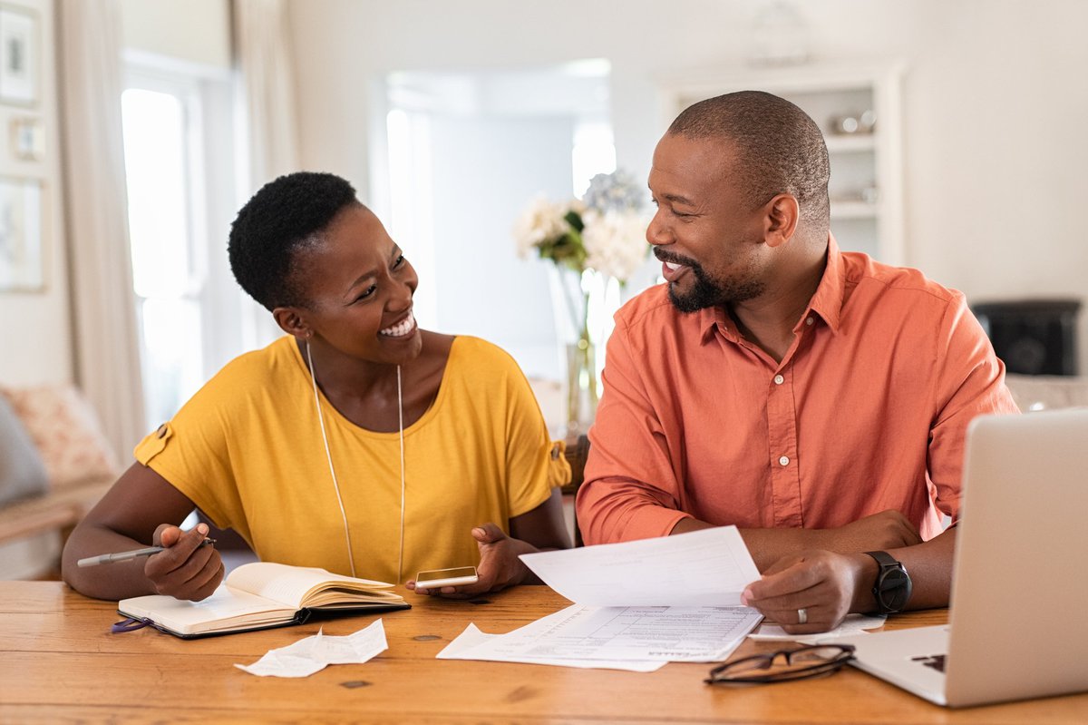 A smiling couple looking at paperwork at a table.