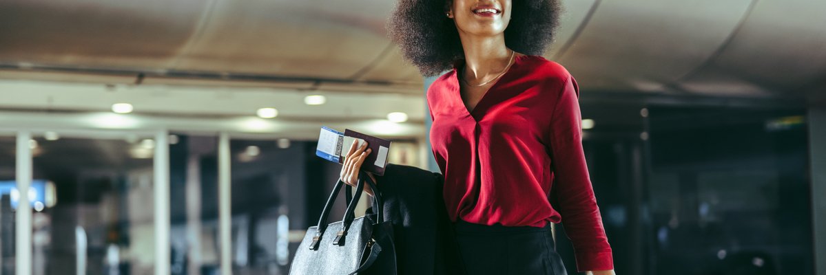 Smiling traveler walks through airport with luggage in tow.