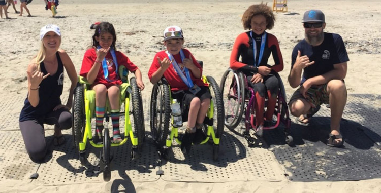 Children in wheelchairs on a beach with a grant-funded Access Trax portable pathway.