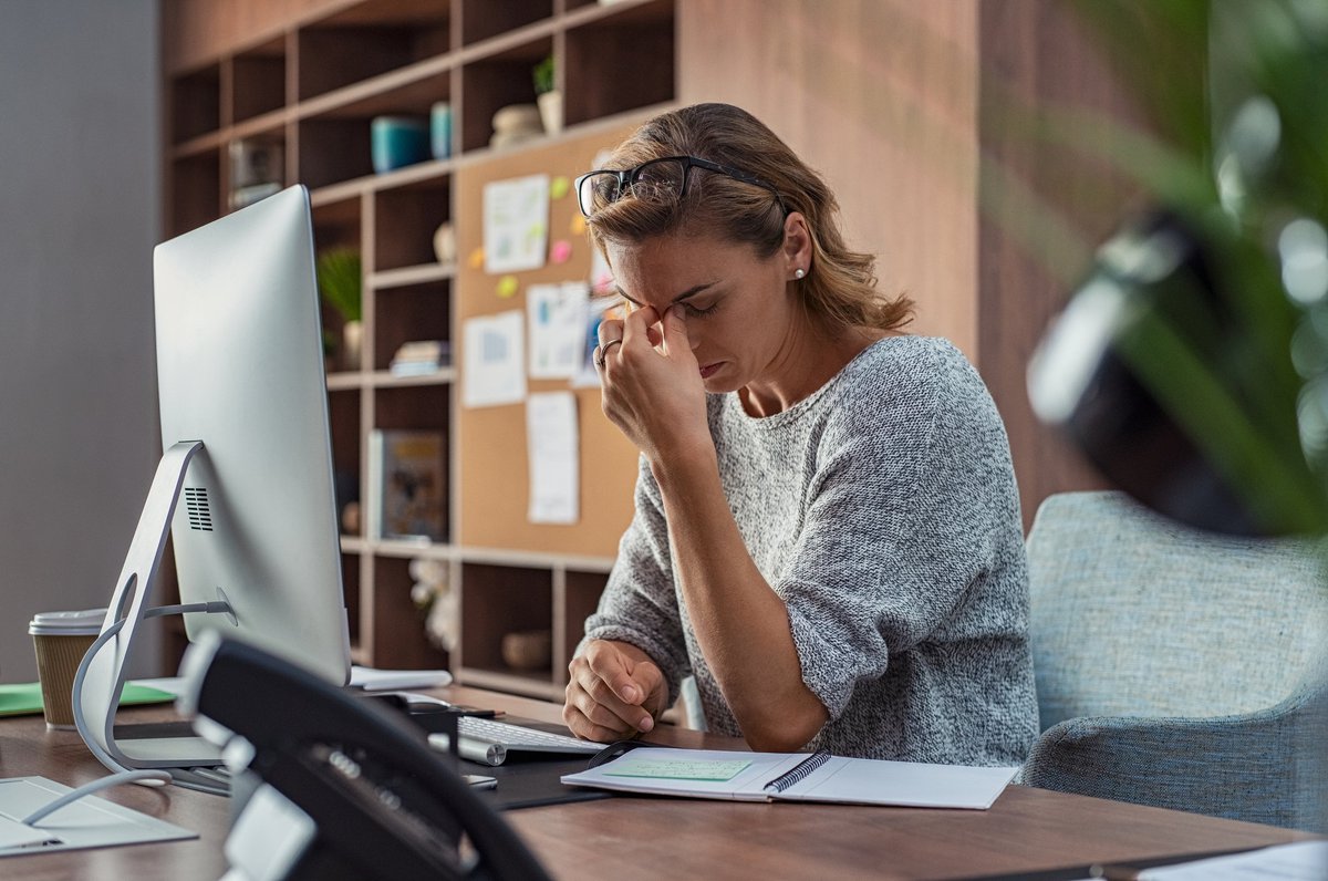 A stressed woman sitting at a desk in an office.