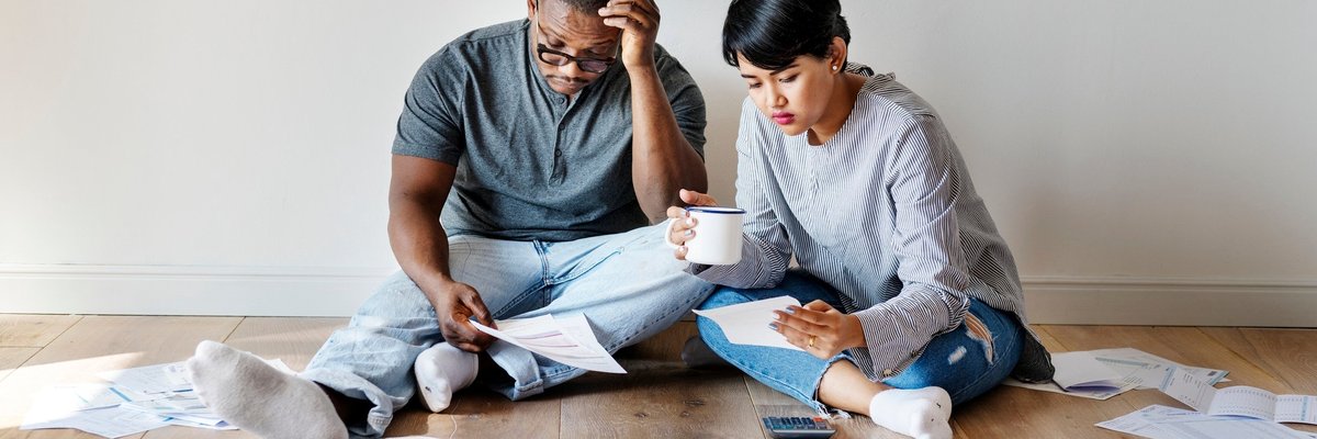 Two people sitting on the ground surrounded by papers.