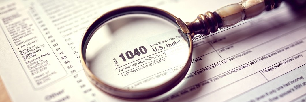 A magnifying glass lies over a tax form.