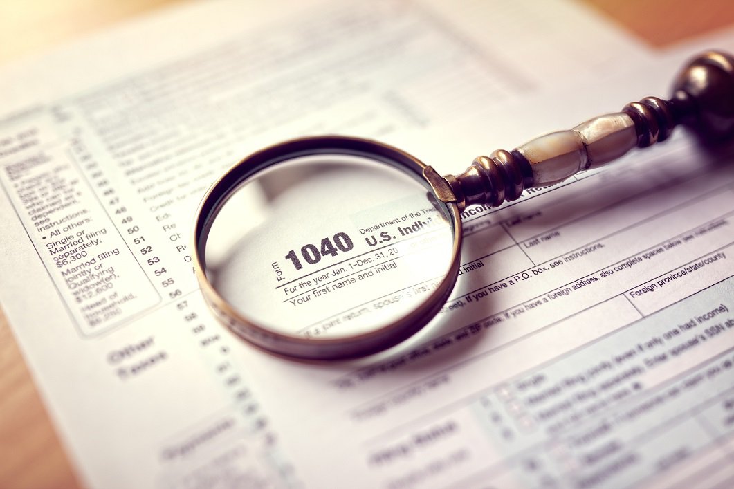 A magnifying glass lies over a tax form.