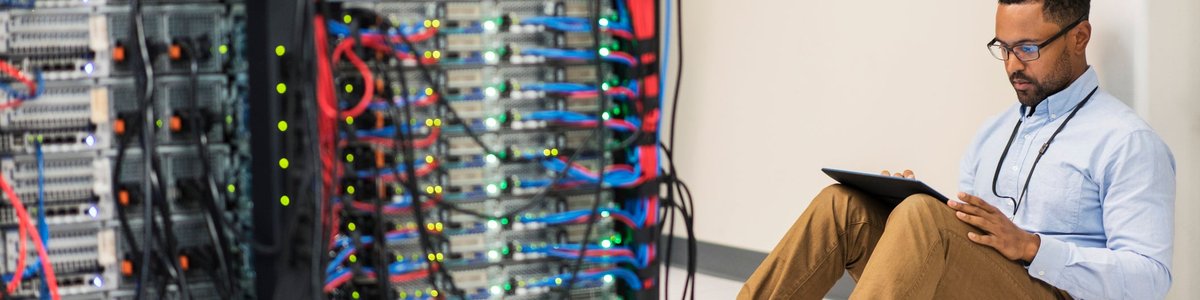 Technician sitting on floor with tablet in a server room.