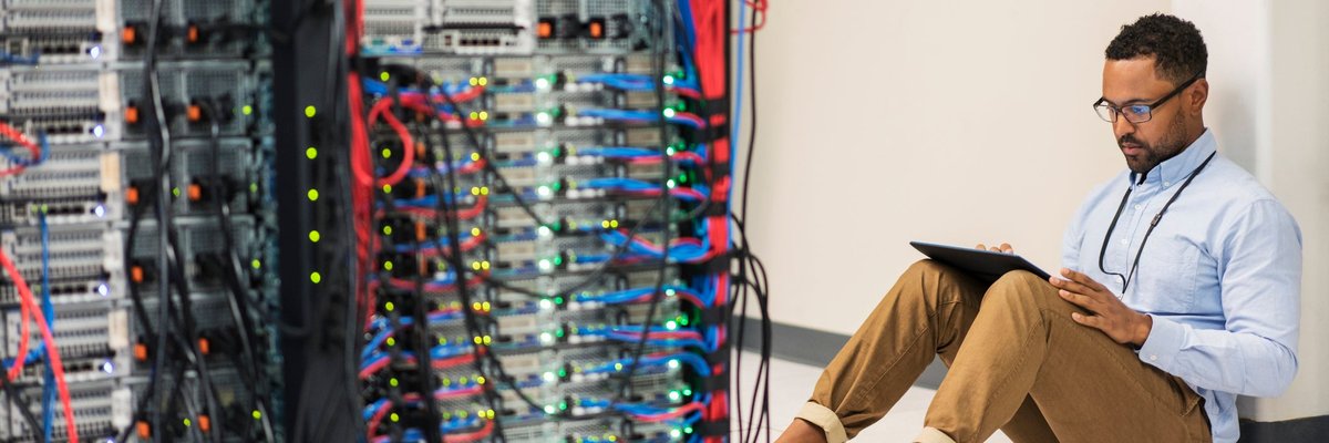 Technician sitting on floor with tablet in a server room.