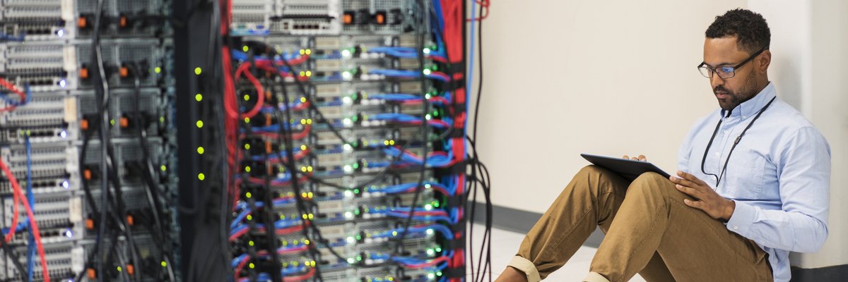 Technician sitting on floor with tablet in a server room.
