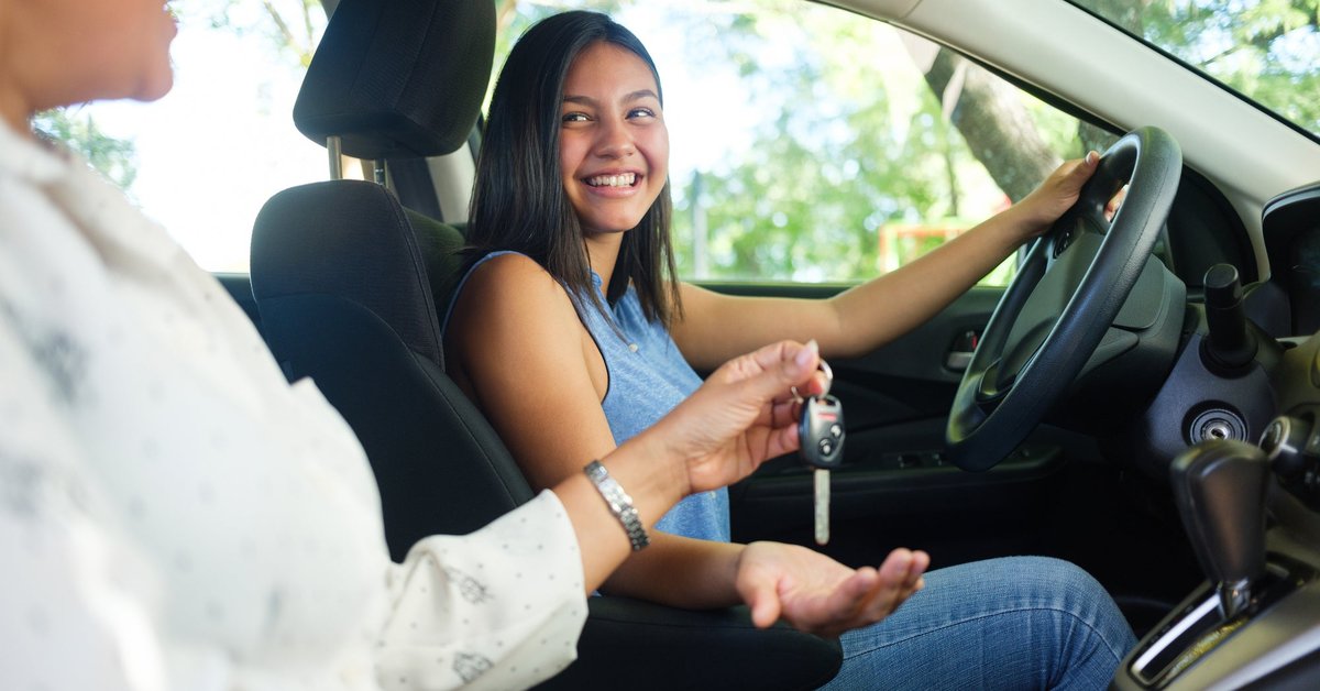 Teen girl in the driver's seat of a vehicle with a parent sitting passenger.