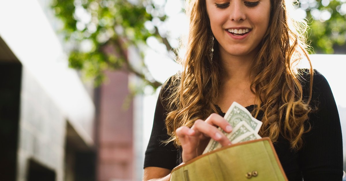Teen taking cash out of her wallet.