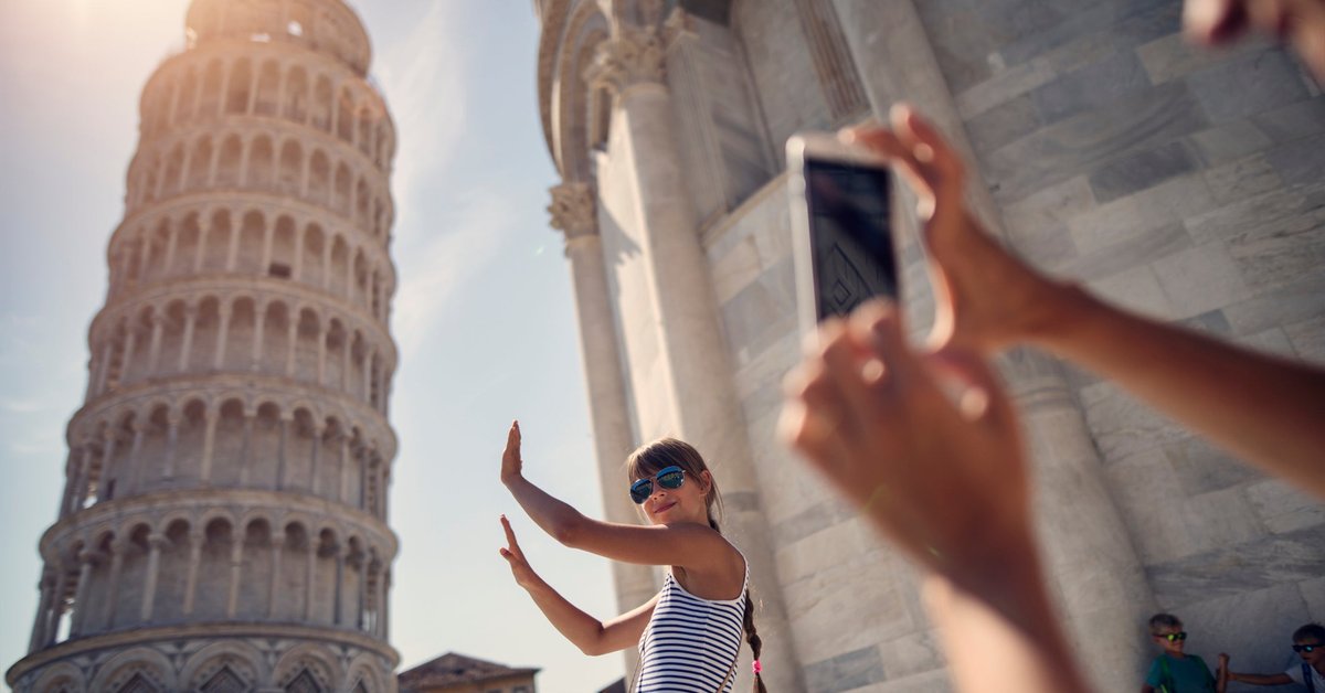 Tourist taking selfie with the leaning tower in Italy.
