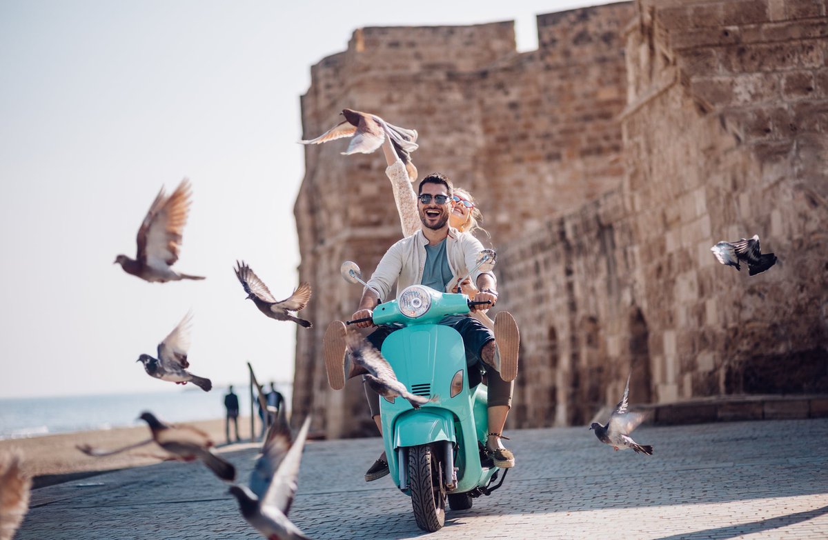 Tourists riding a motorized scooter through an old European city.