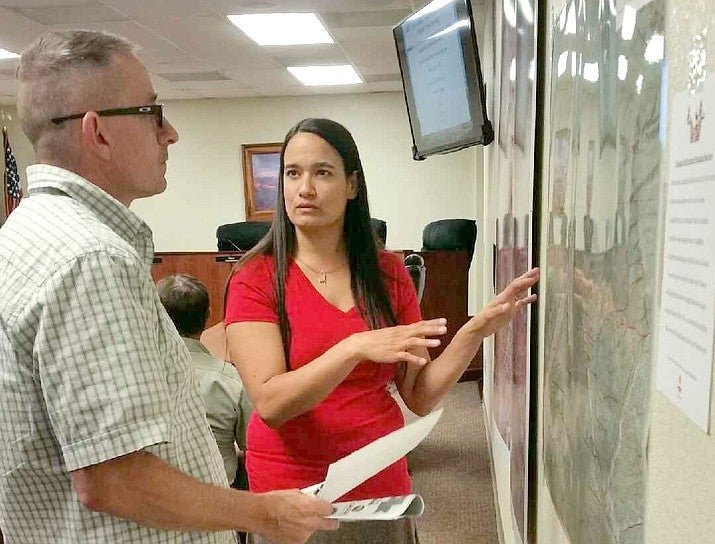 A photograph of Sirena Rana talking to a man while pointing at a map of a wilderness area.