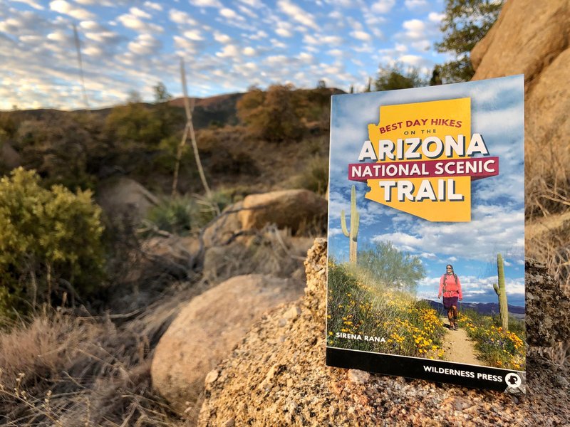 A photo of Sirena Rana’s book, Best Day Hikes on the Arizona National Scenic Trail, sitting on a rock in the Arizona wilderness.