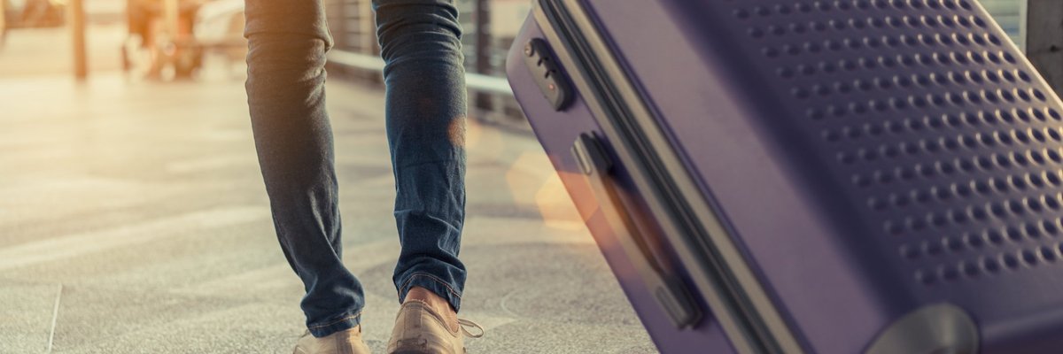 Man pulling suitcase behind him in an airport.