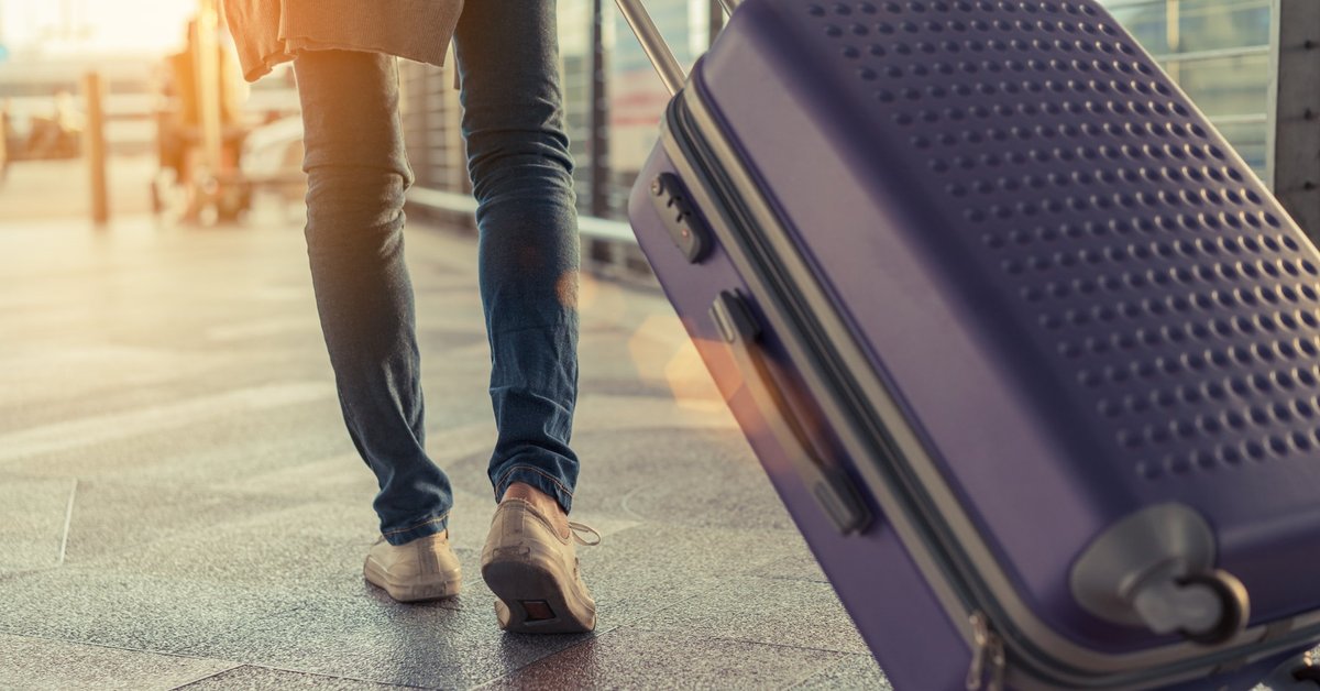 Man pulling suitcase behind him in an airport.