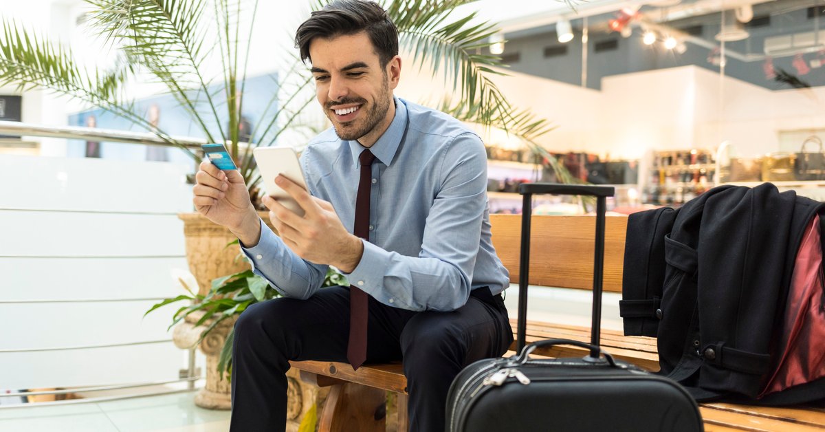 Traveler at airport with luggage, phone, and credit card.