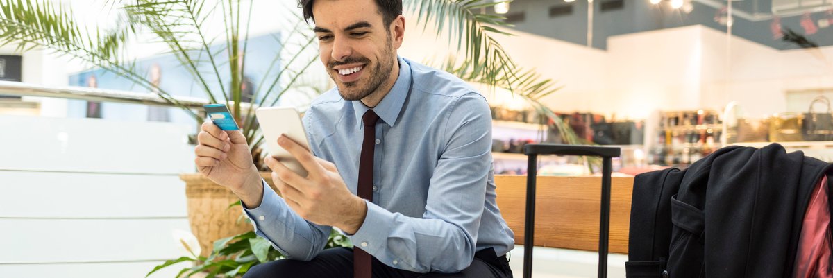 Traveler at airport with luggage, phone, and credit card.