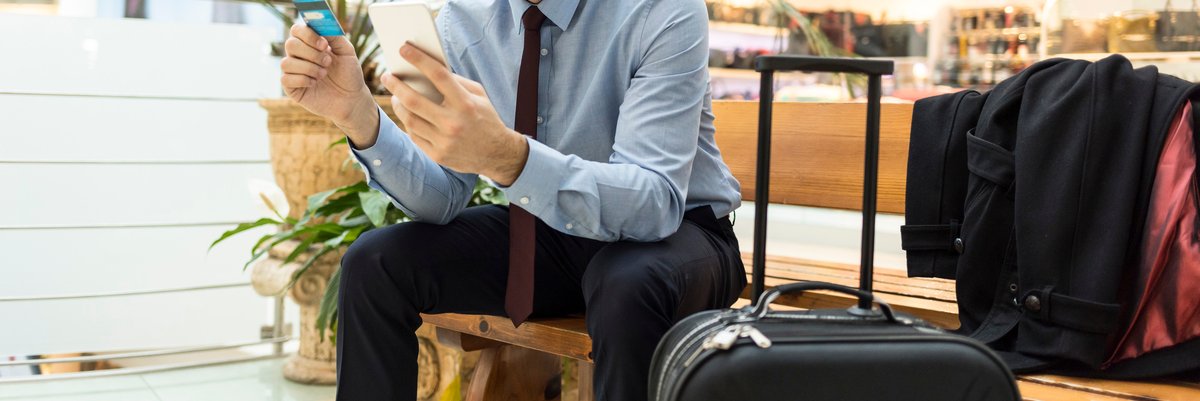 Traveler at airport with luggage, phone, and credit card.