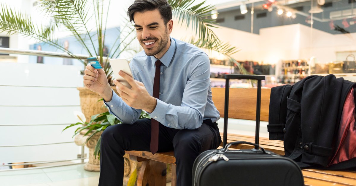 Traveler at airport with luggage, phone, and credit card.