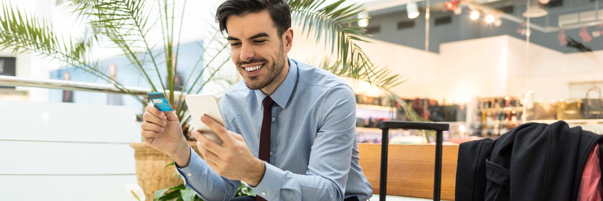 Traveler at airport with luggage, phone, and credit card.