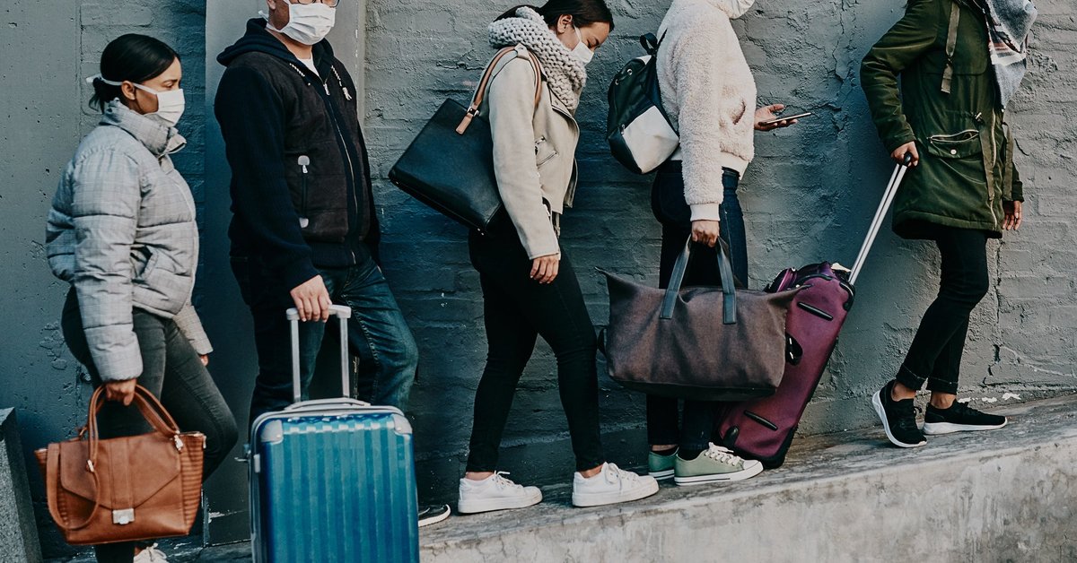 Travelers with masks and luggage during the pandemic.