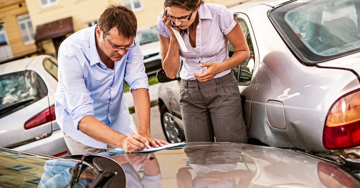 Two adults exchanging information at the site of an auto accident.