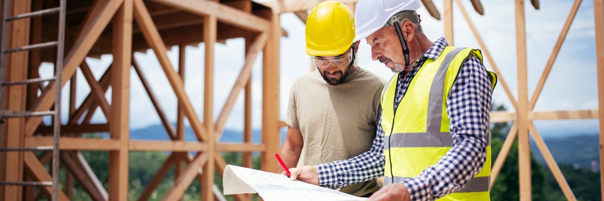 Two builders review blueprints inside an in-process new build home.