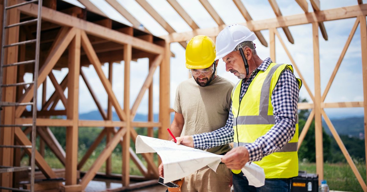 Two builders review blueprints inside an in-process new build home.
