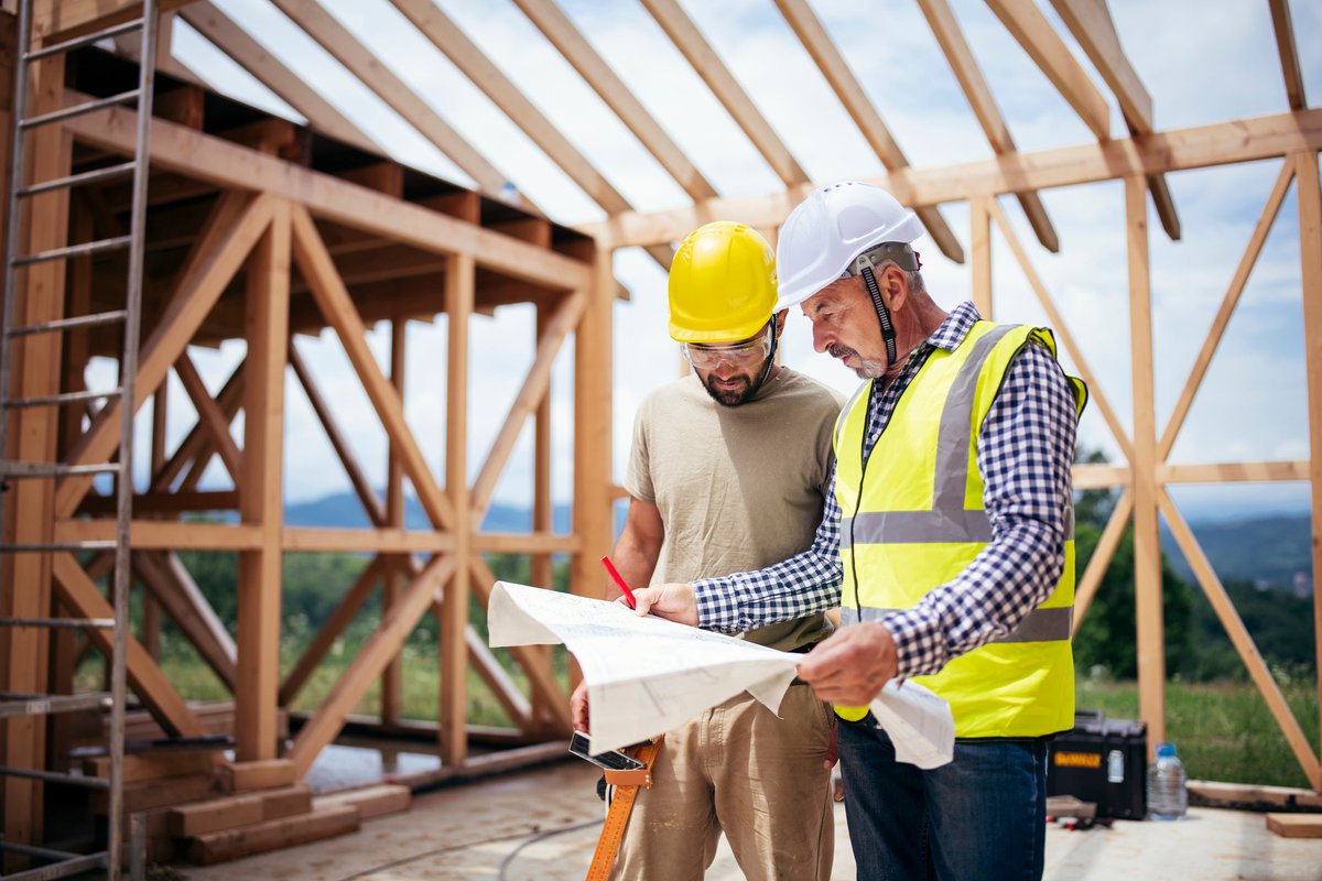 Two builders review blueprints inside an in-process new build home.