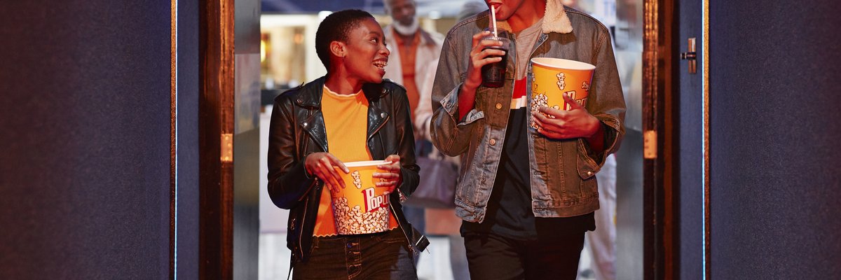 Two smiling friends head into a movie theater.