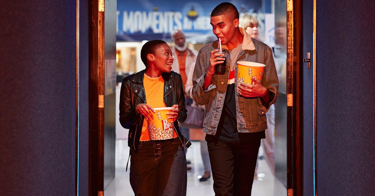 Two smiling friends head into a movie theater.