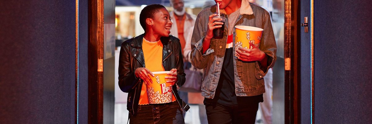 Two smiling friends head into a movie theater.