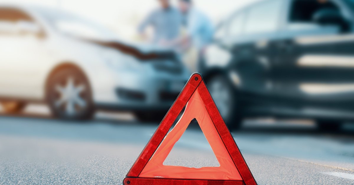 Two men standing at their cars discussing a fender bender.