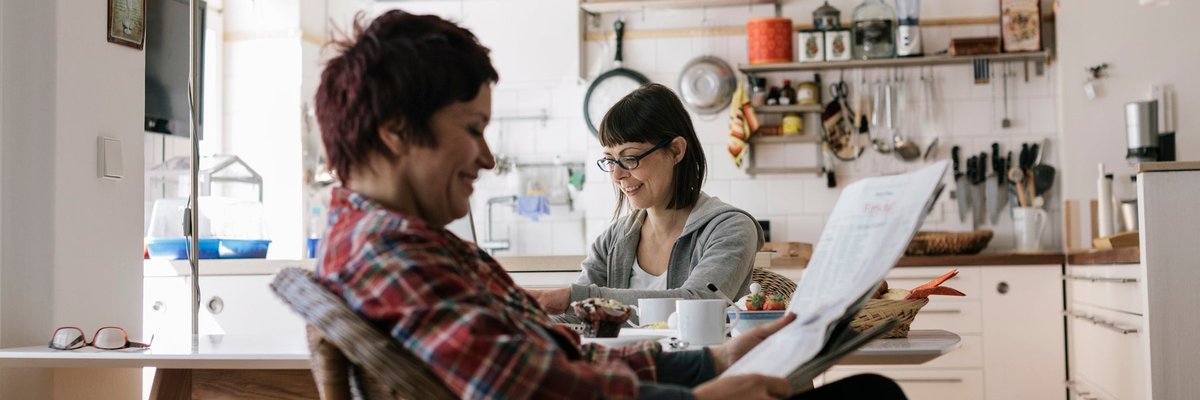 Two people in a kitchen reading the news.