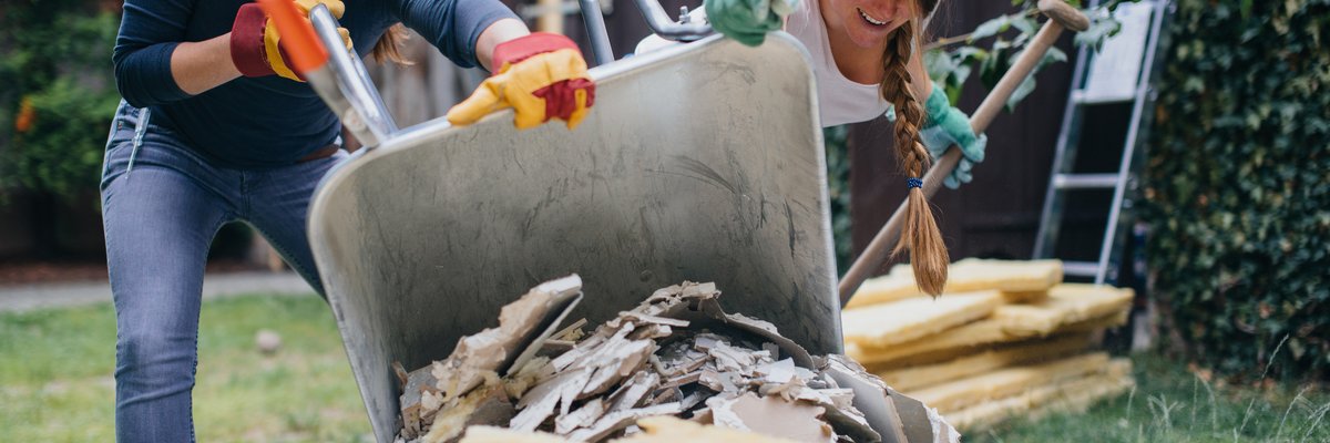 Two women dumping home renovation scraps in a pile outside