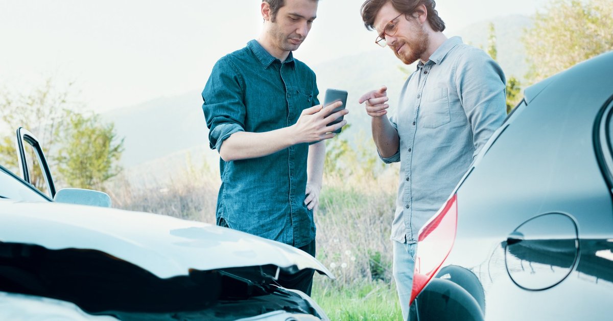 One Driver Taking Picture With Phone Of Car Accident While Other Driver Points At Phone.