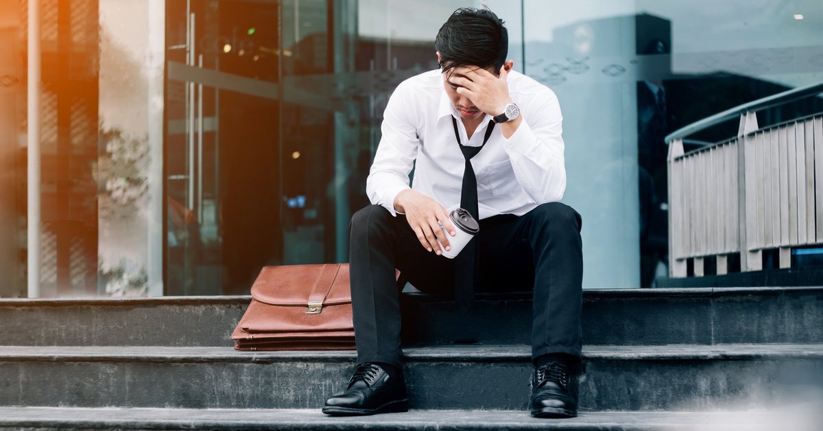 Devastated business man sitting on steps outside of building.