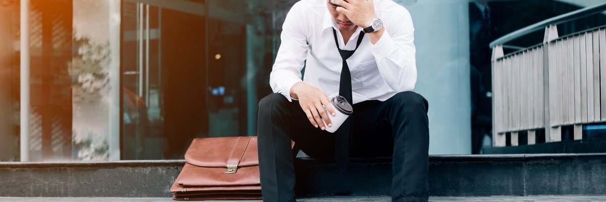 Devastated business man sitting on steps outside of building.