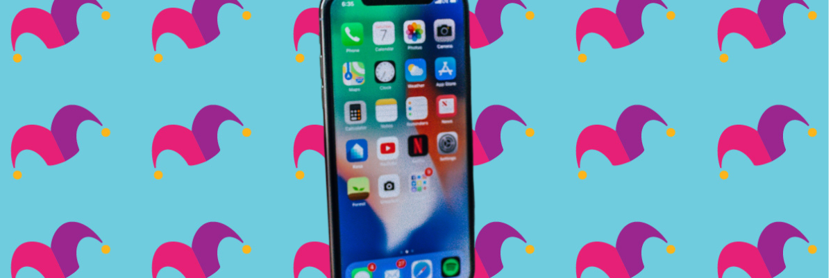 A cell phone on top of a multicolored background covered in jester caps