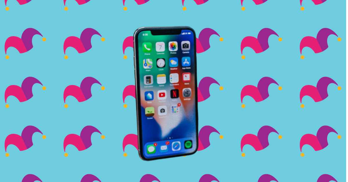 A cell phone on top of a multicolored background covered in jester caps