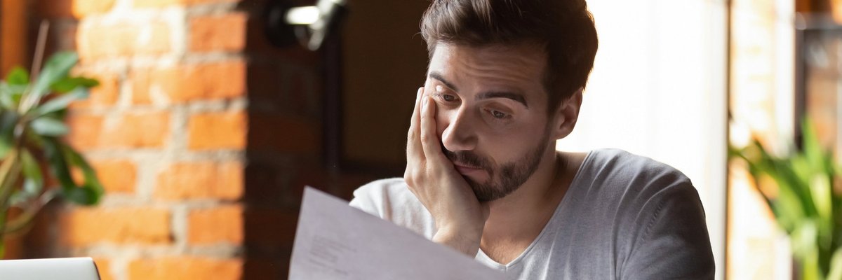 A man looking distressed while reading his credit card bill.