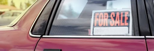Used car with "For Sale" sign in the rear window.