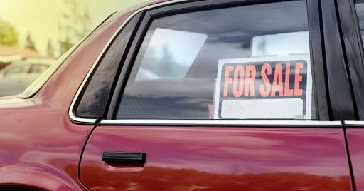 Used car with "For Sale" sign in the rear window.