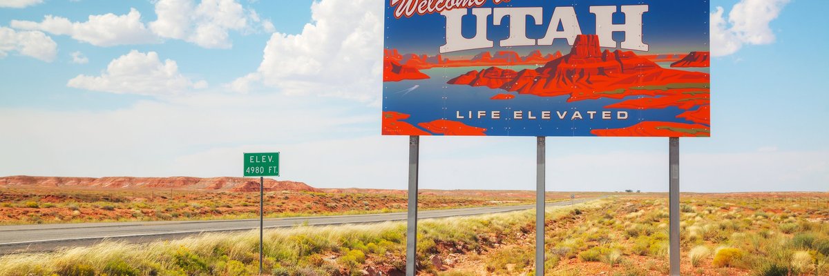 A Welcome to Utah sign next to a desert highway.