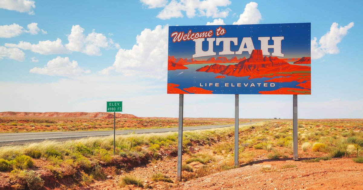 A Welcome to Utah sign next to a desert highway.