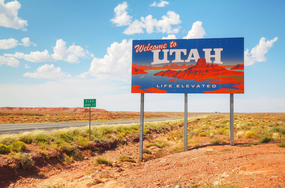A Welcome to Utah sign next to a desert highway.